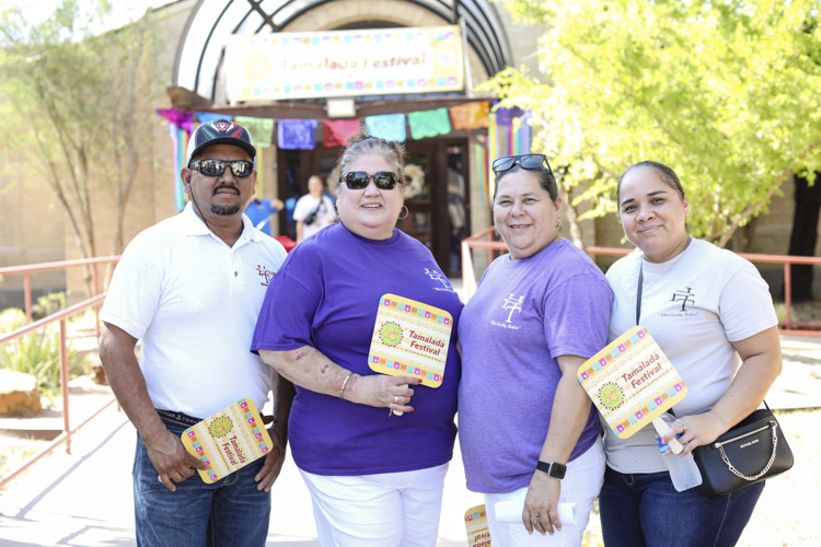 4 people with Tamalada Festival fans in front of museum
