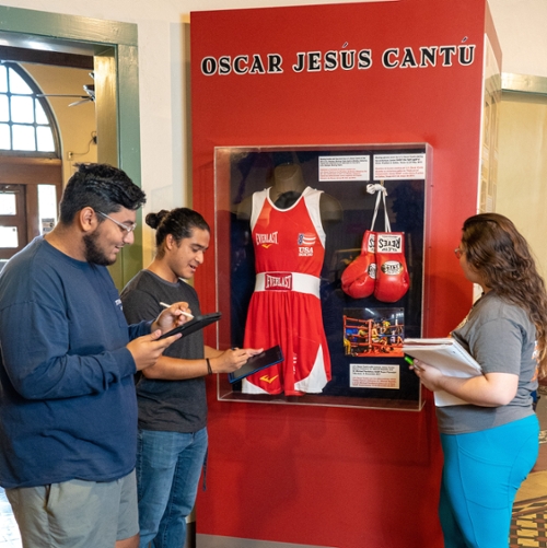 Oscar Cantu exhibit with students photographing the exibit