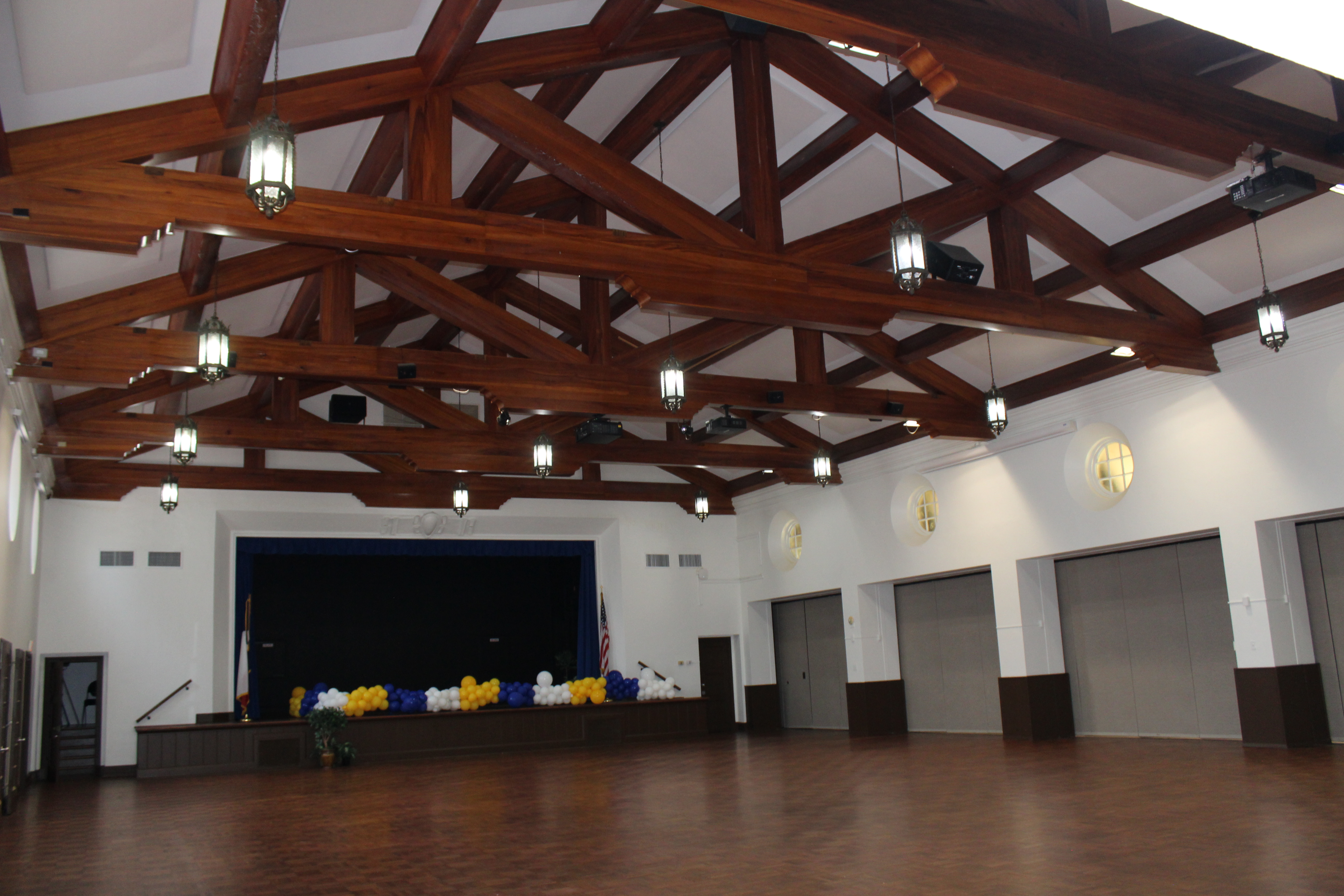 Ballroom A, empty, with a high ceiling featuring newly painted white walls and brown wood staining on the rafters and flooring.