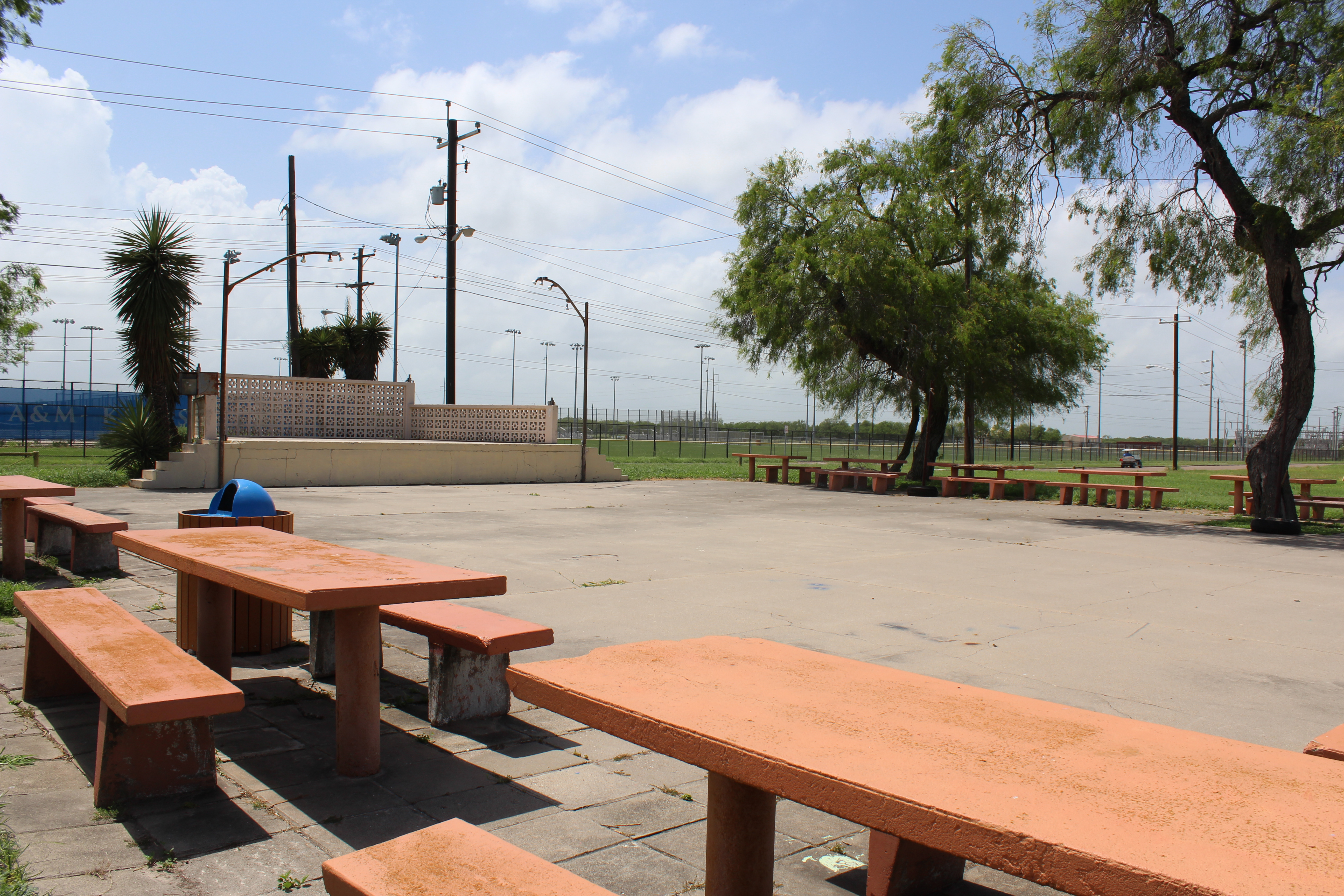 A concrete courtyard with a stage, ringed by bench tables.