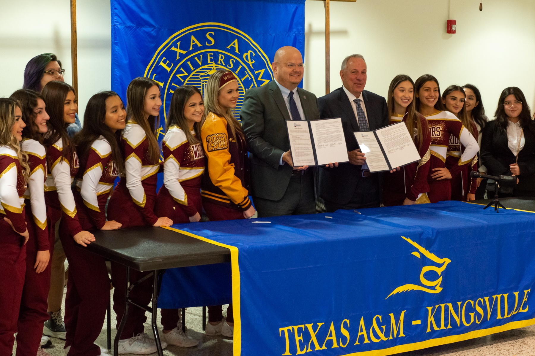 Dr. Robert Vela Jr., president of Texas A&M-Kingsville and Stephen Van Matre, superintendent of the TMISD pose with Tuloso-Midway cheerleaders after signing an MOU concerning dual credit courses.