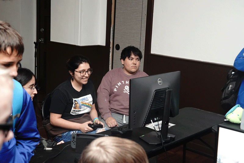 Female Esports player smiles while looking at her monitor as a male looks on
