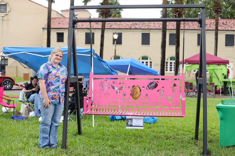 Carlee Wiginton stands to the left of her pink porch swing