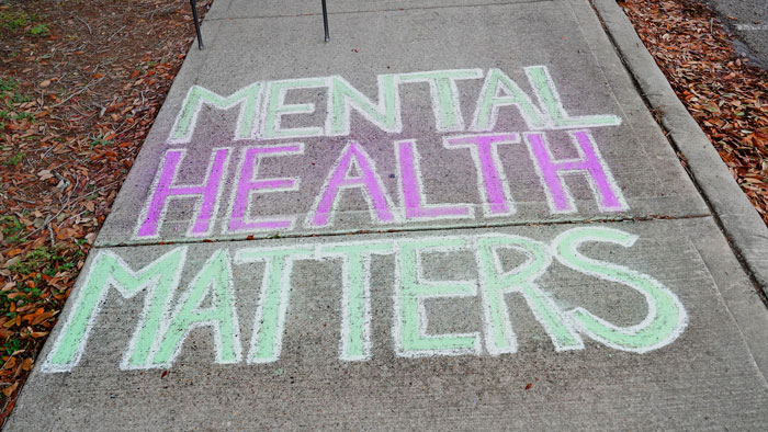 Chalk message on a sidewalk reading “MENTAL HEALTH MATTERS.”