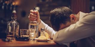 man clinching bottle of alcohol at a bar