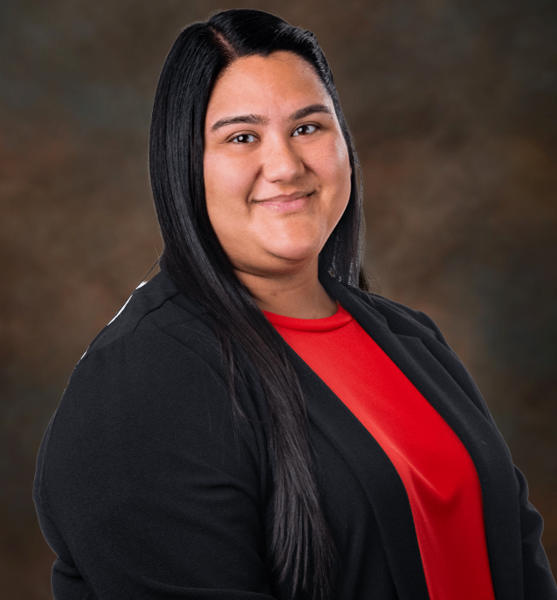 Professional portrait of a smiling woman with long black hair, wearing a black blazer over a red shirt.